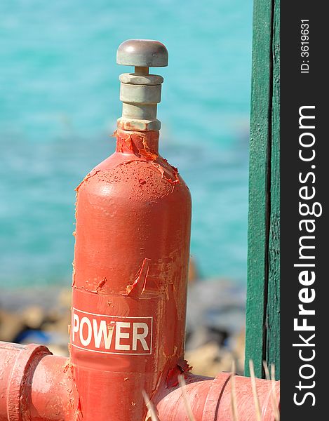 A close up view of a red gas cylinder attached to an above ground pipeline with water from the Red Sea in the background. A close up view of a red gas cylinder attached to an above ground pipeline with water from the Red Sea in the background.