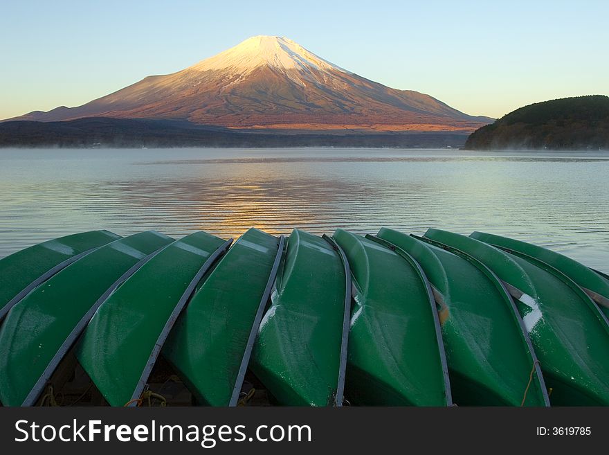 Green rowboats on the lakeshore with Mount Fuji