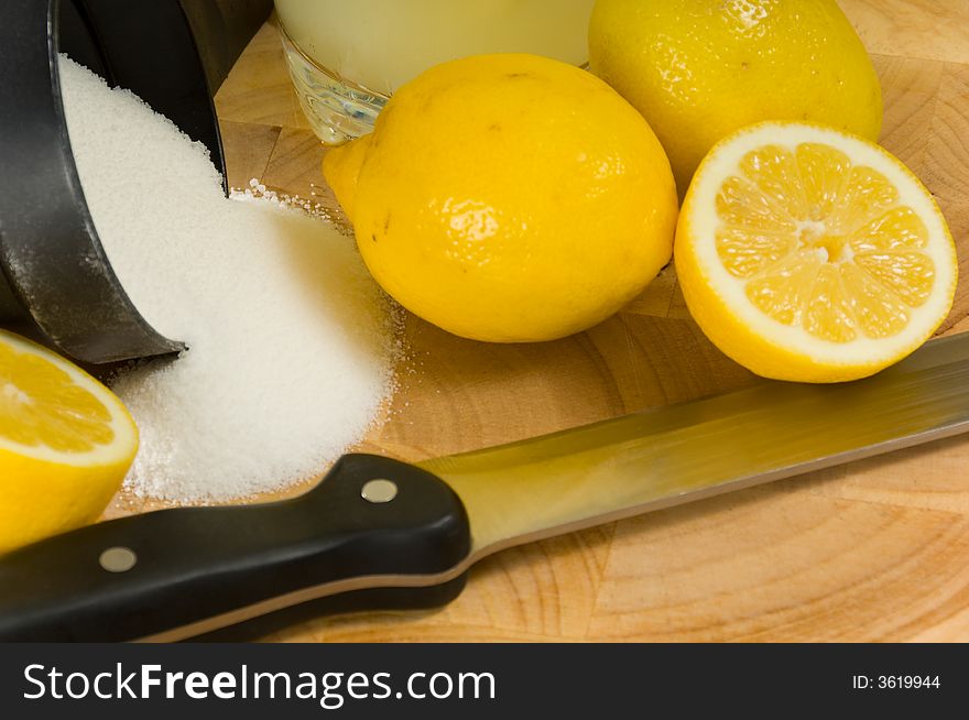 Lemons, sugar and kinfe on cutting board.  ingredients for lemonade. Lemons, sugar and kinfe on cutting board.  ingredients for lemonade