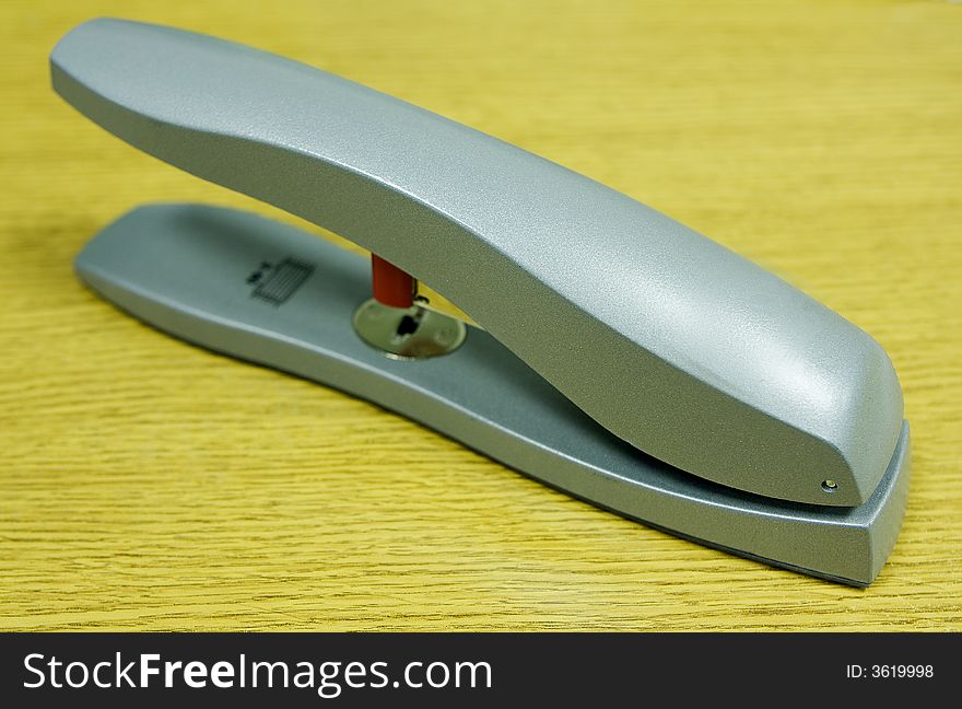 Silver coloured stapler on an office desk nice colours. Silver coloured stapler on an office desk nice colours