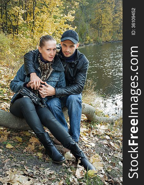 In love couple sitting on a log on the background of a forest pond couple in love