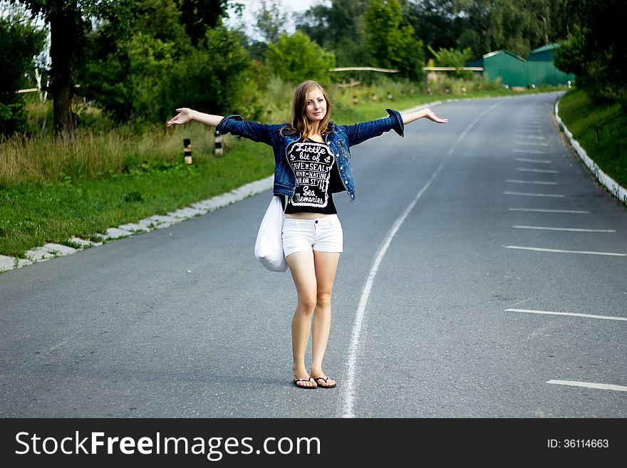 Young happy woman with a bag on a road