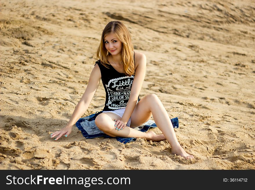 Lonely smiling girl relaxing on the sunny sea sand beach