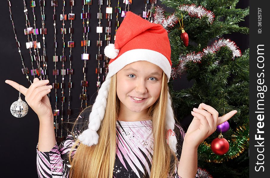 Smyling pretty girl with Santa hat on decorating tree. Smyling pretty girl with Santa hat on decorating tree