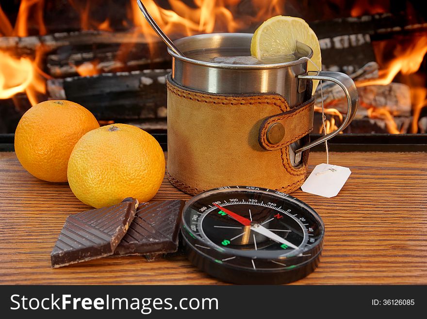 Mug of Tea, Hip Flask and a Compass on a Wooden Plank at Campfire. Mug of Tea, Hip Flask and a Compass on a Wooden Plank at Campfire