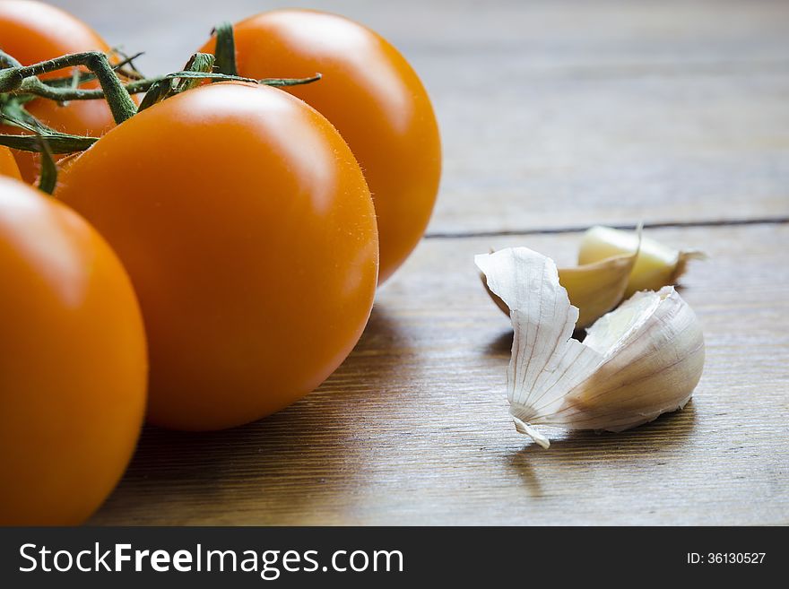 Fresh juicy orange tomatoes and garlic closeup with focus on garlic