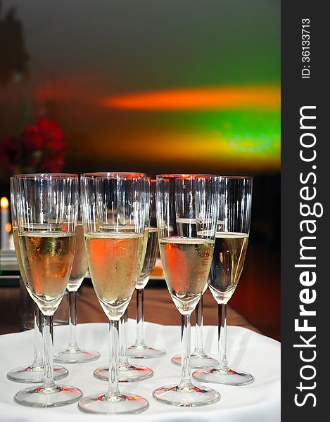 A number of champagne glasses filled with bubbles, waiting to be served at a reception. A number of champagne glasses filled with bubbles, waiting to be served at a reception.