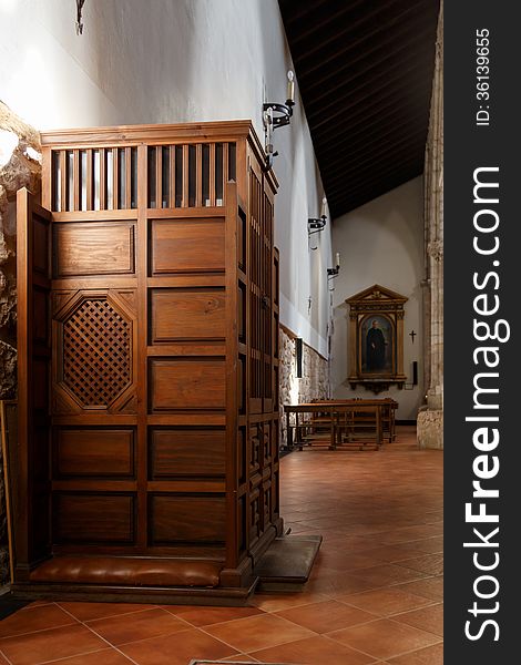 Side view of a confessional in a Catholic church in the back seats and a painting of a saint. Side view of a confessional in a Catholic church in the back seats and a painting of a saint