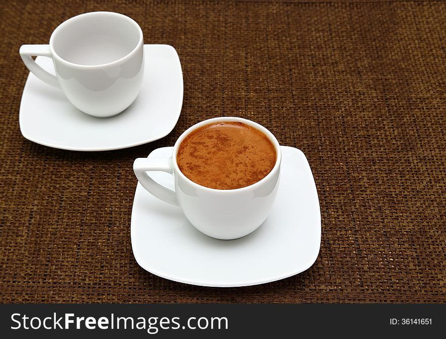 Two white cups with greek coffee on sacking. Dark background