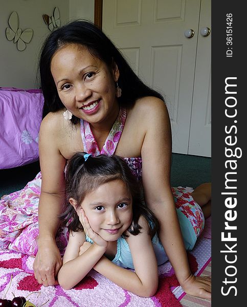 A Filipino mother and her daughter spend time together relaxing in the girls bedroom. A Filipino mother and her daughter spend time together relaxing in the girls bedroom.