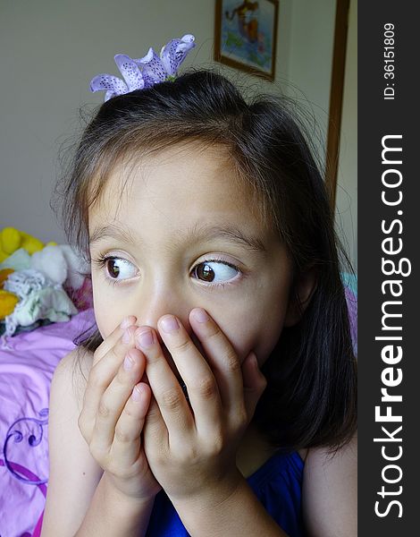 A frightened young Asian girl holds her hands over her mouth as she stares with her eyes wide open. A frightened young Asian girl holds her hands over her mouth as she stares with her eyes wide open.