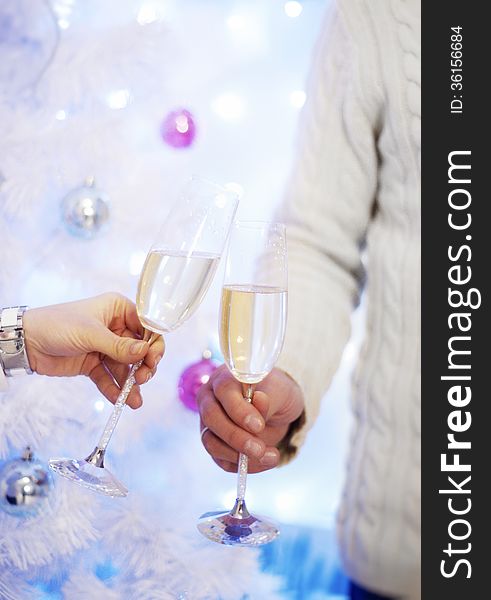 Two wine glasses in hands on background of New Year tree