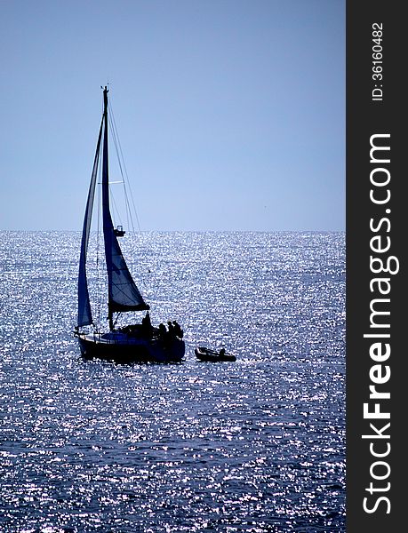 Sailing yacht against the sun on a sparkling blue sea. Sailing yacht against the sun on a sparkling blue sea
