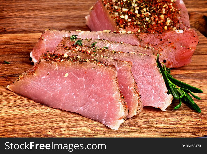 Delicious Sliced Roast Beef with Herbs and Spices closeup on Wooden Cutting Board