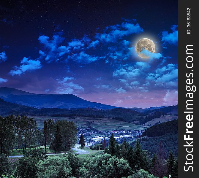 Autumn landscape at night. village on the hillside. forest on the mountain covered with red and yellow leaves. over the mountains the beam of light falls on a clearing at the top of the hill. Autumn landscape at night. village on the hillside. forest on the mountain covered with red and yellow leaves. over the mountains the beam of light falls on a clearing at the top of the hill.