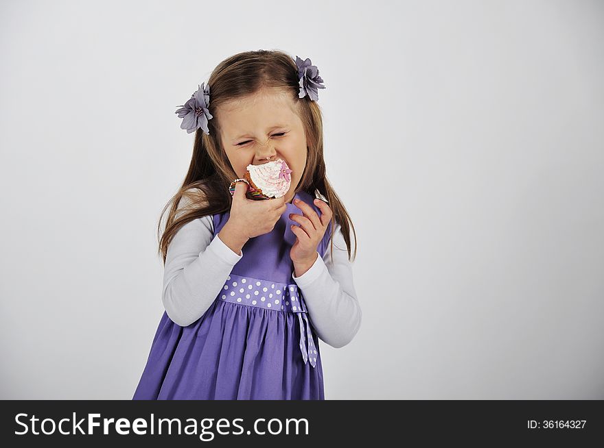 Cute little girl in a studio eating a delicious cupcakes. Cute little girl in a studio eating a delicious cupcakes.