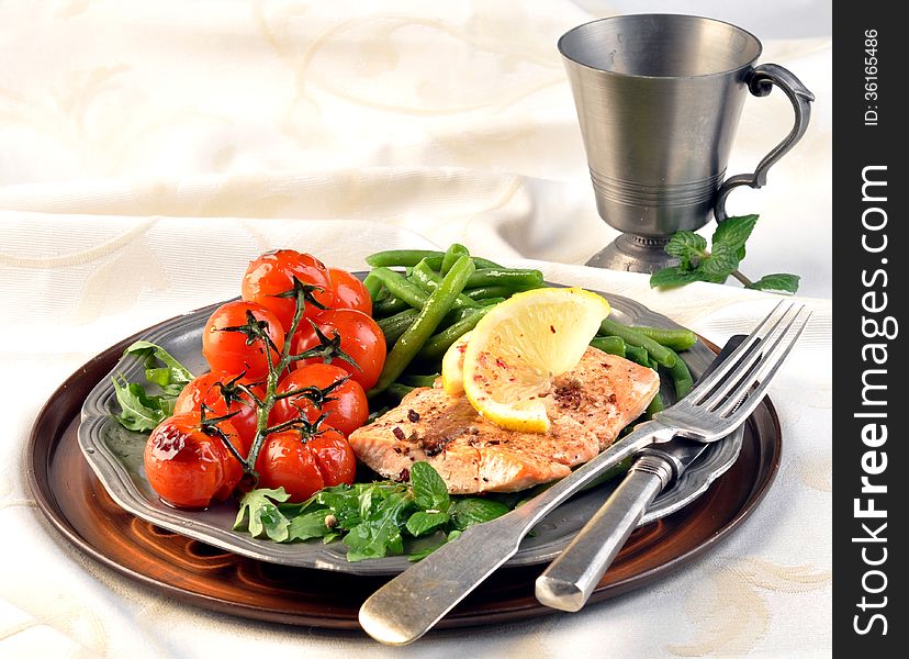 Salmon with green beans and tomatoes on a silver plate