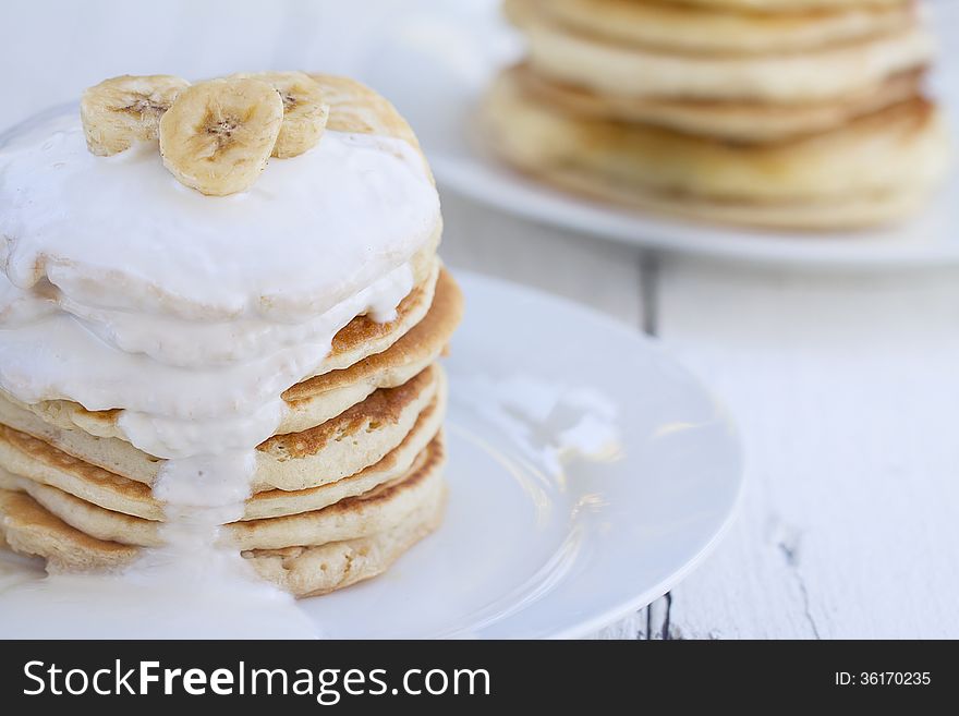 Stacks of Pancakes with sour cream and pieces of banana