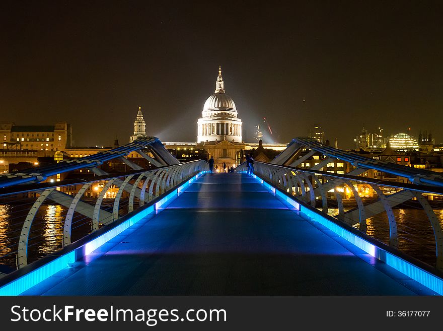 View along the illuminated Millennium Bridge across River Thames towards also illuminated St. Paul's Cathedral on a dark autumn evening. View along the illuminated Millennium Bridge across River Thames towards also illuminated St. Paul's Cathedral on a dark autumn evening