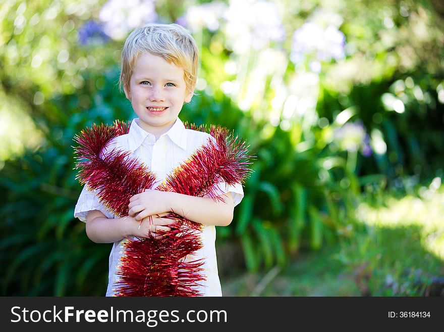 Little boy with tinsel wrapped around him for Christmas. Little boy with tinsel wrapped around him for Christmas.