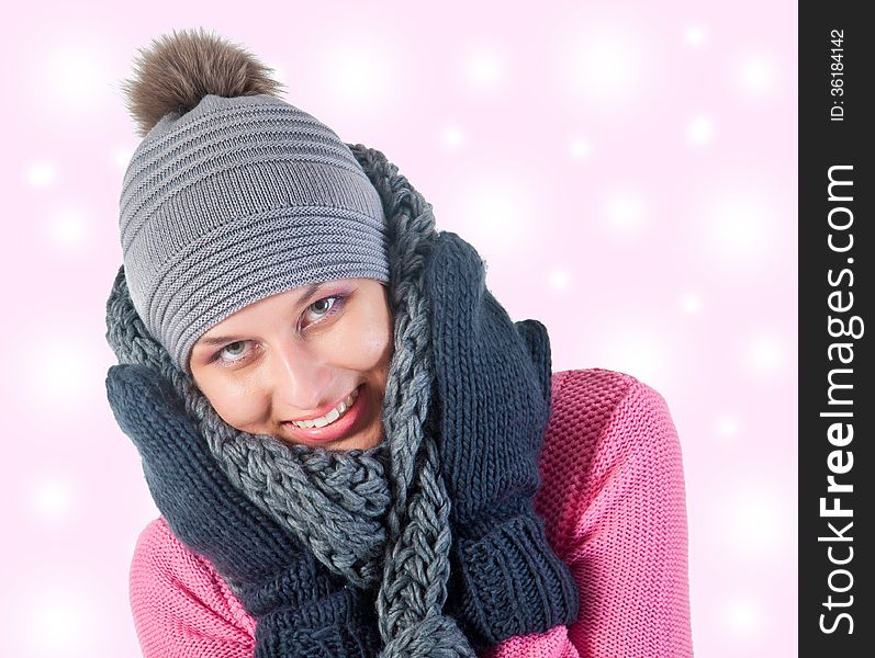 Beautiful woman in warm clothing closeup portrait. pink and snowly background
