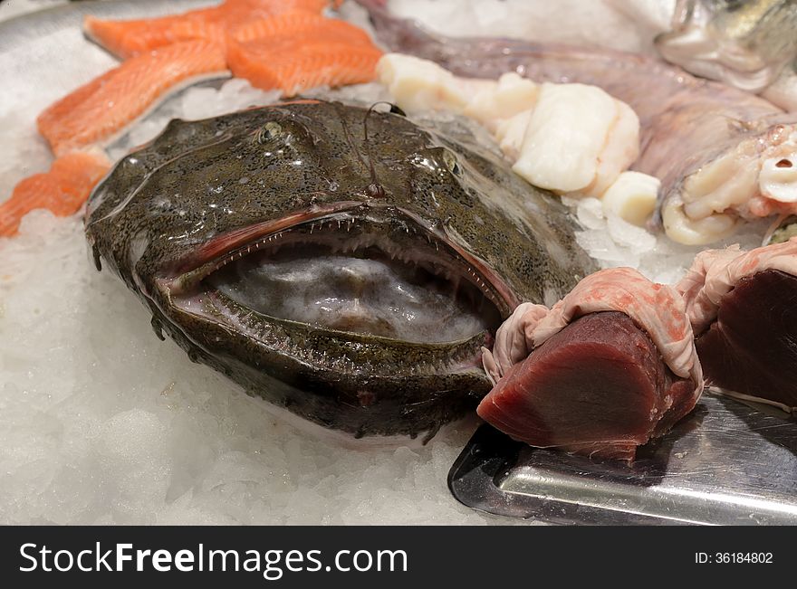 Fresh monkfish, salmon filet and tuna steak in a shop. The fish is lying cooled on crushed ice to beware its freshness.