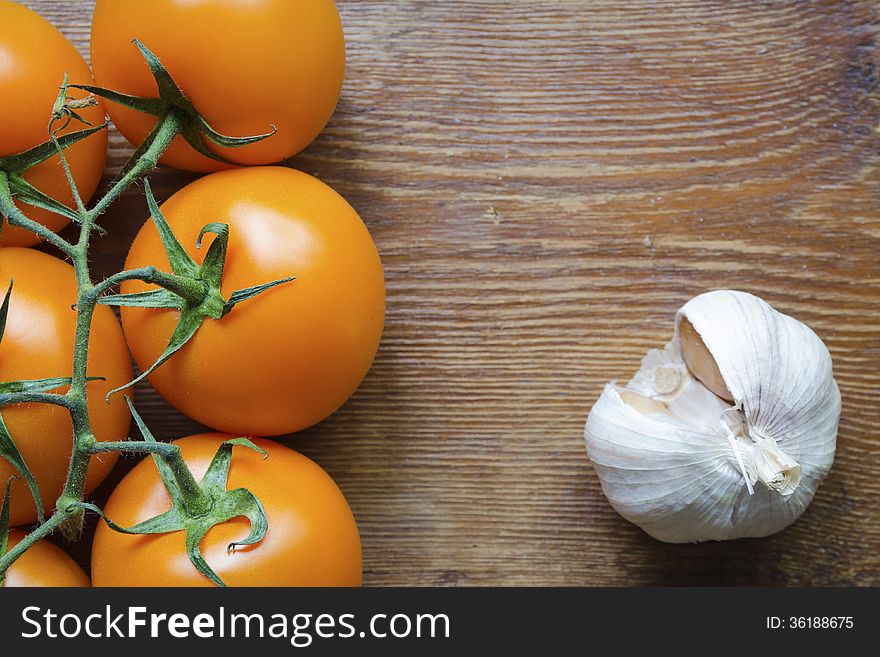 Fresh juicy orange tomatoes and garlic closeup with focus on tomatoes