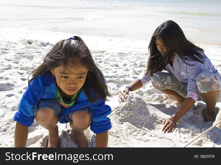 Picture of two kids playing with the sand on the beach. Picture of two kids playing with the sand on the beach