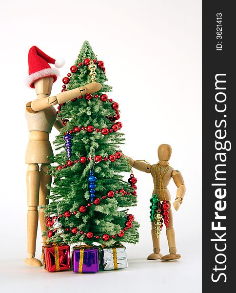 Adult and child figurines decorating a christmas tree against white background. Adult and child figurines decorating a christmas tree against white background.