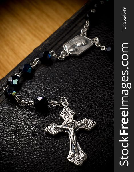 Rosary crucifix draped over antique leather bible. Rosary crucifix draped over antique leather bible