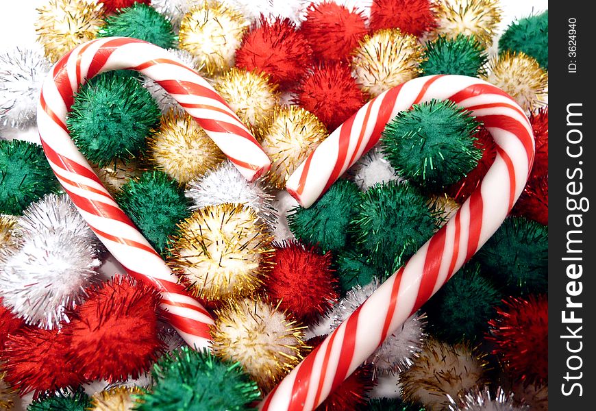 Pair of candy canes nestled in colorful shiny pompons. Pair of candy canes nestled in colorful shiny pompons
