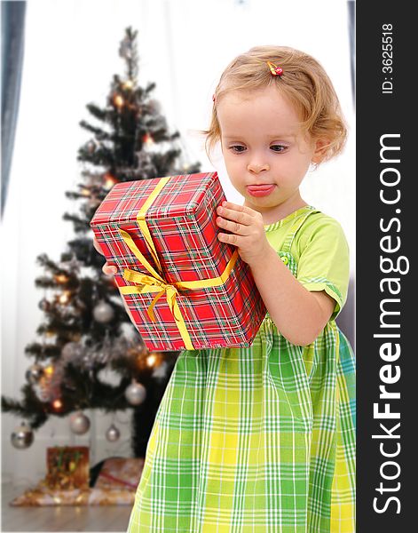Happy young girl with wrapped present, Christmas tree in background. Happy young girl with wrapped present, Christmas tree in background.