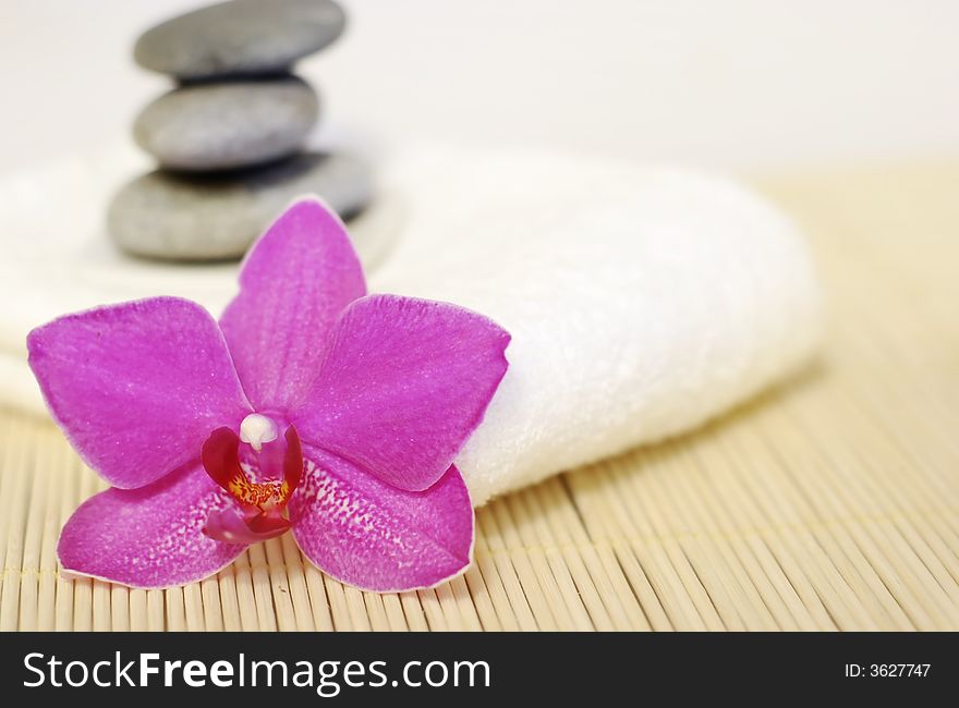 Pebble stones on white towel with orchid flower. Pebble stones on white towel with orchid flower