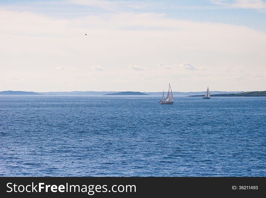 Two sailboats in blue waters near the coast of Maine