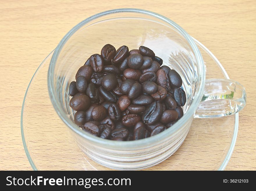 Coffee beans in cup on wood table background