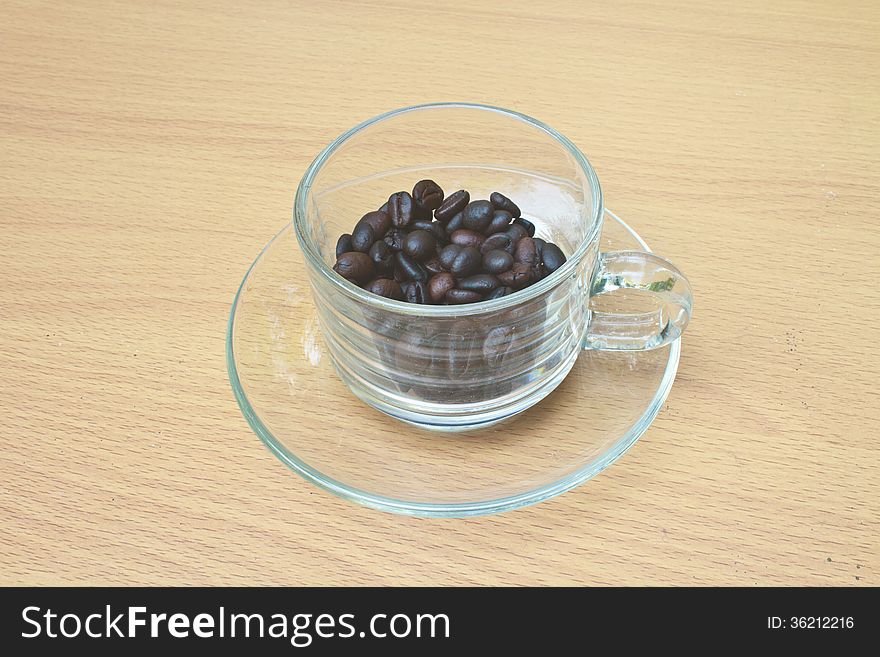 Coffee beans in cup on wood table background