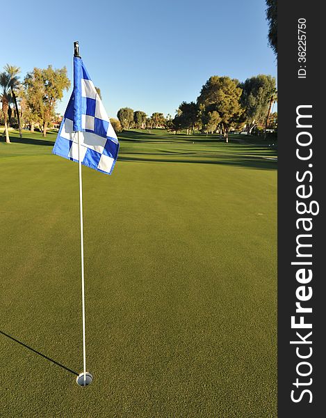 Eye level view of a golf green with a checkered flag. Eye level view of a golf green with a checkered flag