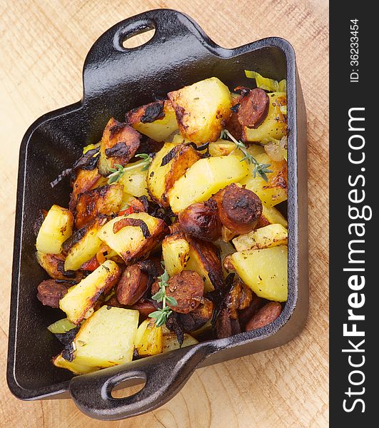 Tasty Homemade Roasted Sausages and Potato Stew in Frying Pan on Wooden background