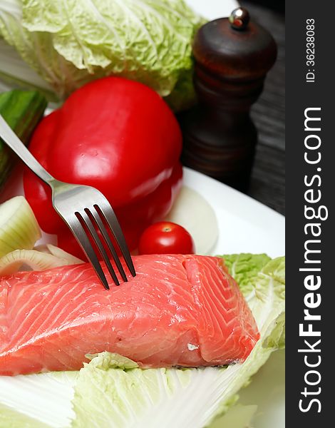 Closeup of filleted salmon and vegetables on plate near fork. Closeup of filleted salmon and vegetables on plate near fork