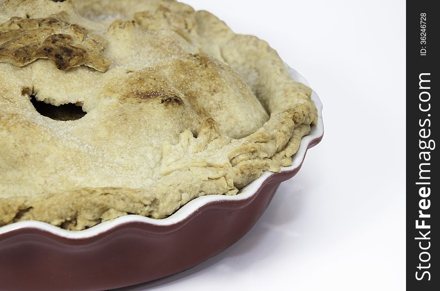 Section of homemade apple pie in a red and white ceramic dish against a white background. Section of homemade apple pie in a red and white ceramic dish against a white background