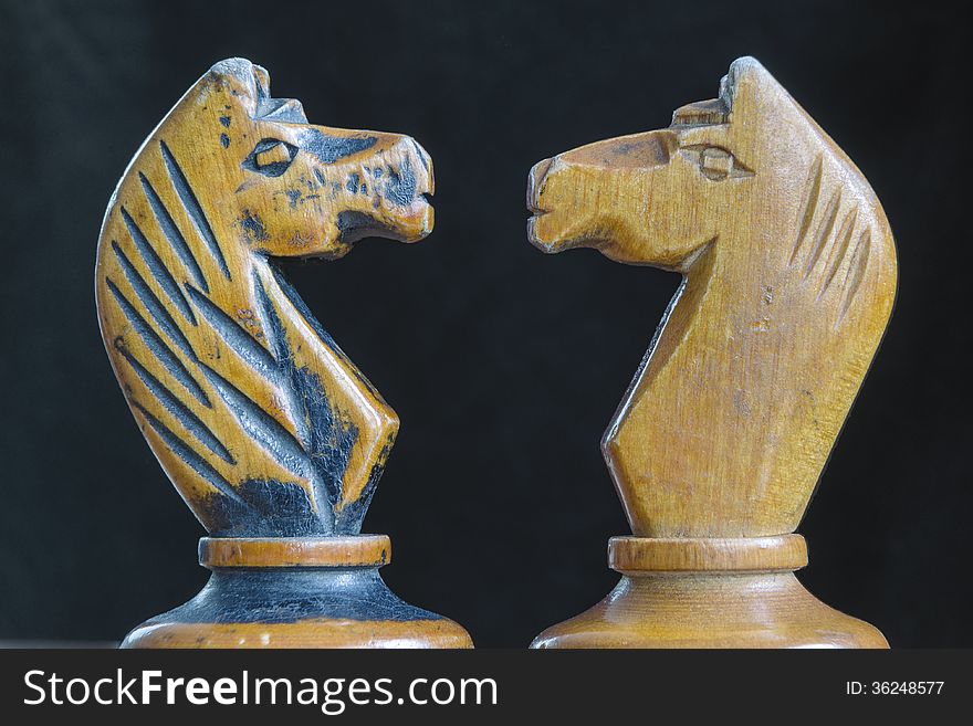 Black and white wooden chess knights facing each other