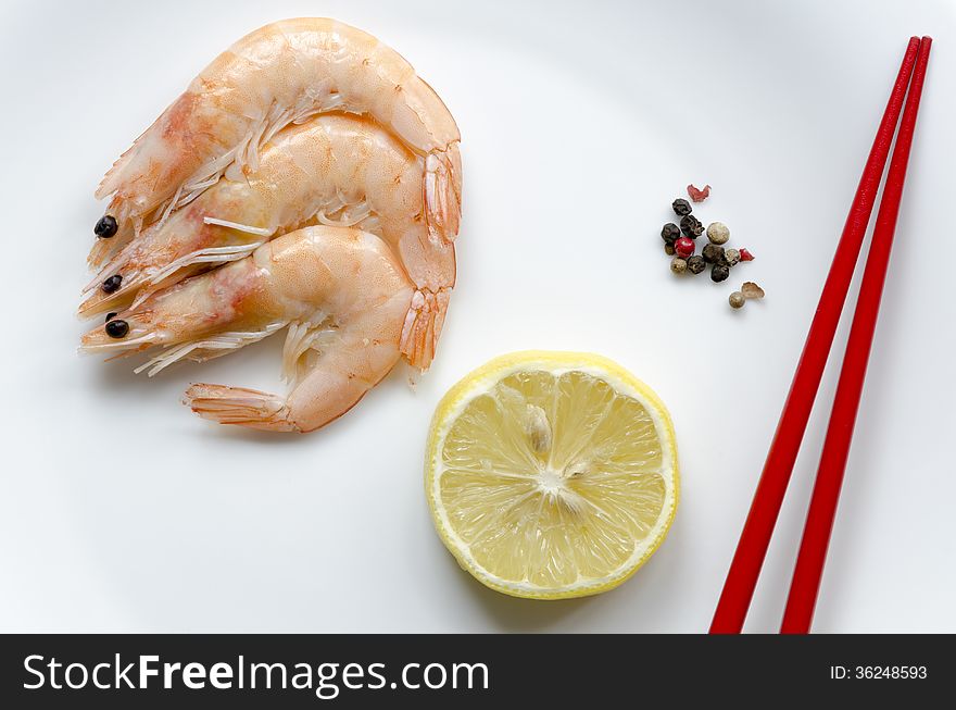 Three shrimps with lemon slice and red chopsticks on white plate. Three shrimps with lemon slice and red chopsticks on white plate