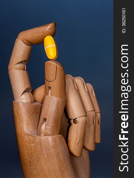 A robot like wooden hand, with a pill between two fingers. A robot like wooden hand, with a pill between two fingers.