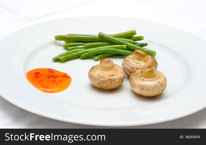 Mushrooms and green beans with sauce on a plate