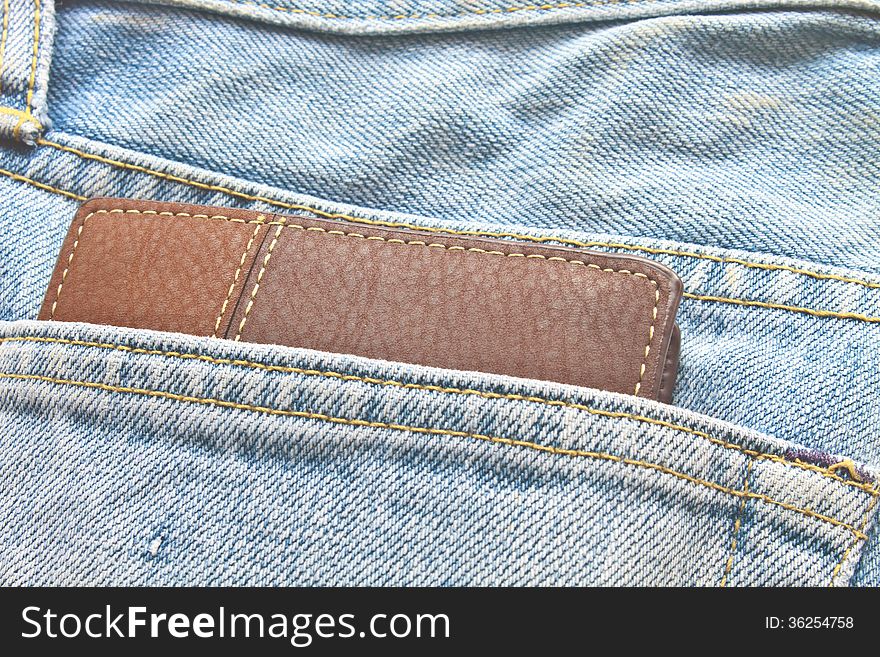 Brown wallet in jeans trousers back pocket, close up texture