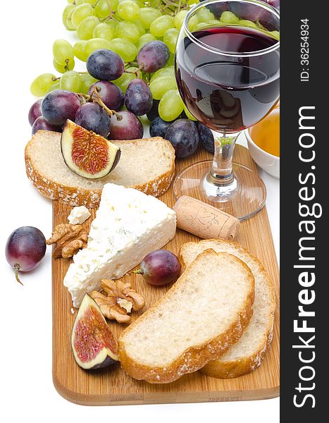 Snacks - cheese, bread, figs, grapes, nuts and red wine on a wooden board isolated on white
