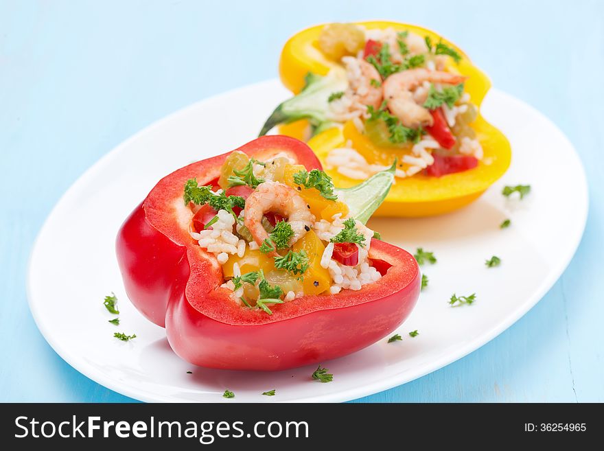 Stuffed peppers with salad of rice and shrimp on a blue background, close-up, horizontal. Stuffed peppers with salad of rice and shrimp on a blue background, close-up, horizontal