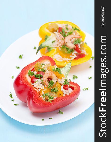 Stuffed peppers with salad of rice and shrimp on a blue background, close-up