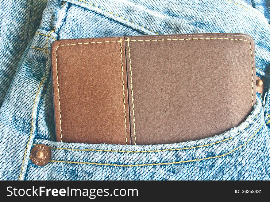 Brown wallet in jeans trousers back pocket, close up texture