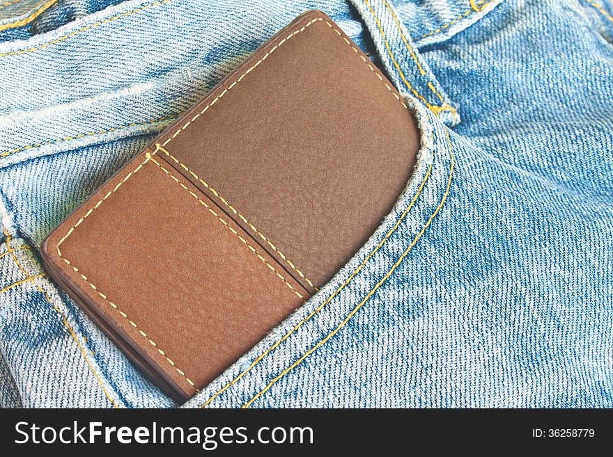 Brown wallet in jeans trousers back pocket, close up texture